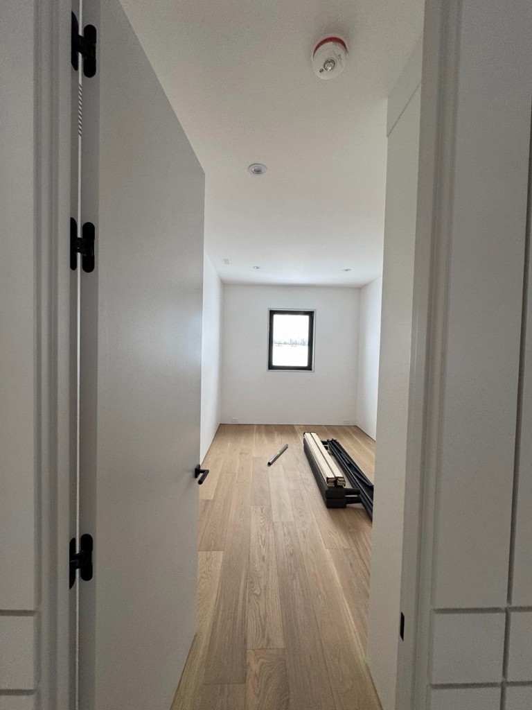 Interior hallway with light grey painted wall paneling and glass railing.