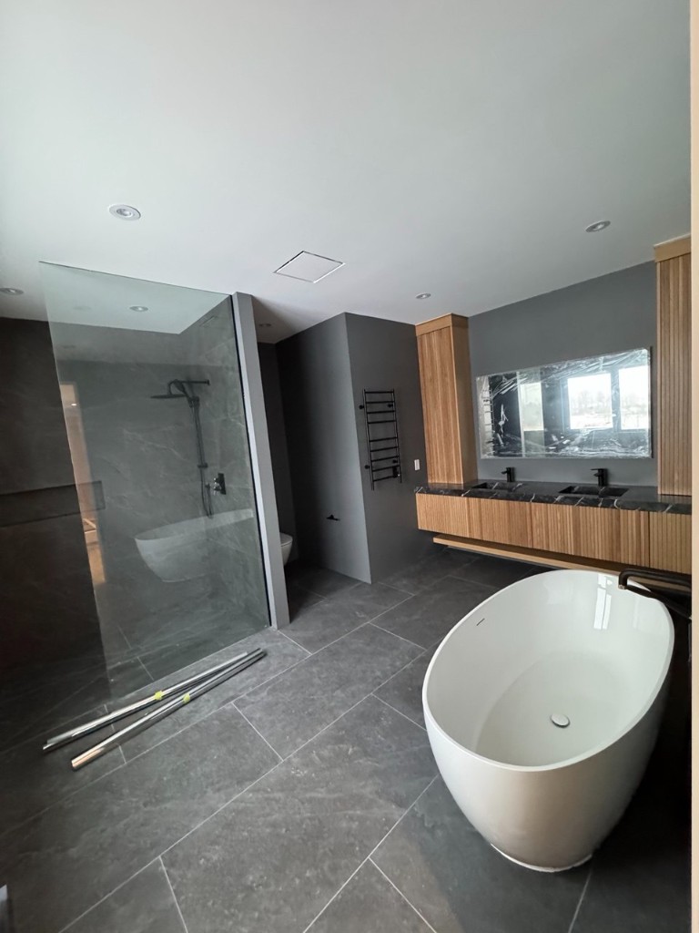 Renovated bathroom with dark grey walls, stone tile, freestanding tub, and black fixtures.