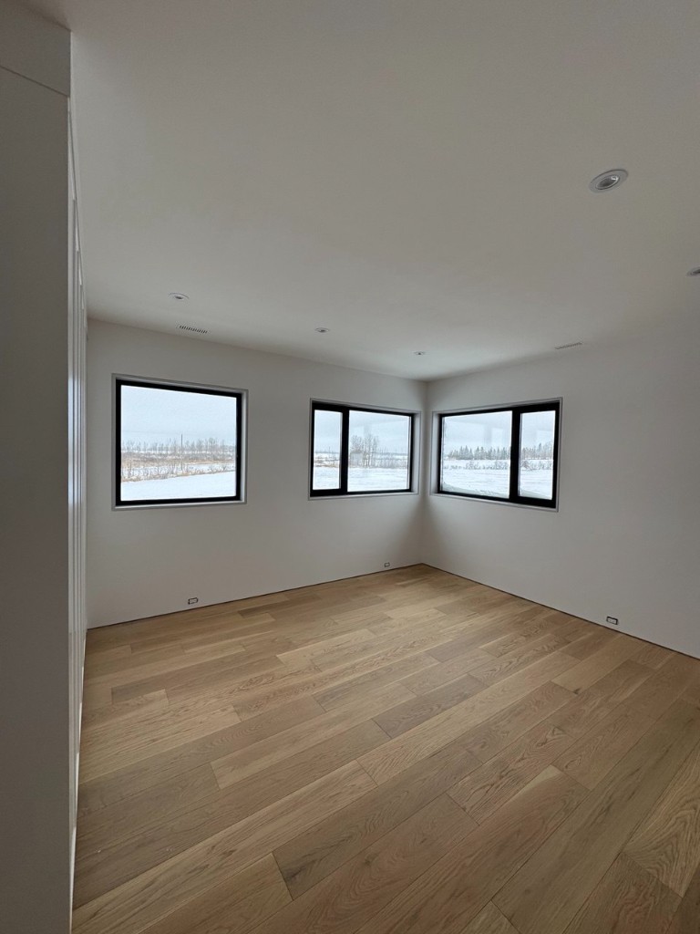 Modern residential interior with light walls, large windows, and hardwood floors.