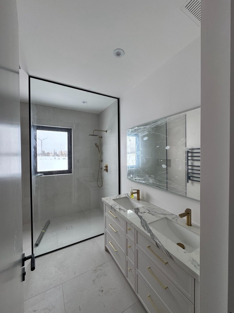 Bathroom with white shaker vanity, marble countertop, gold fixtures, and glass shower.